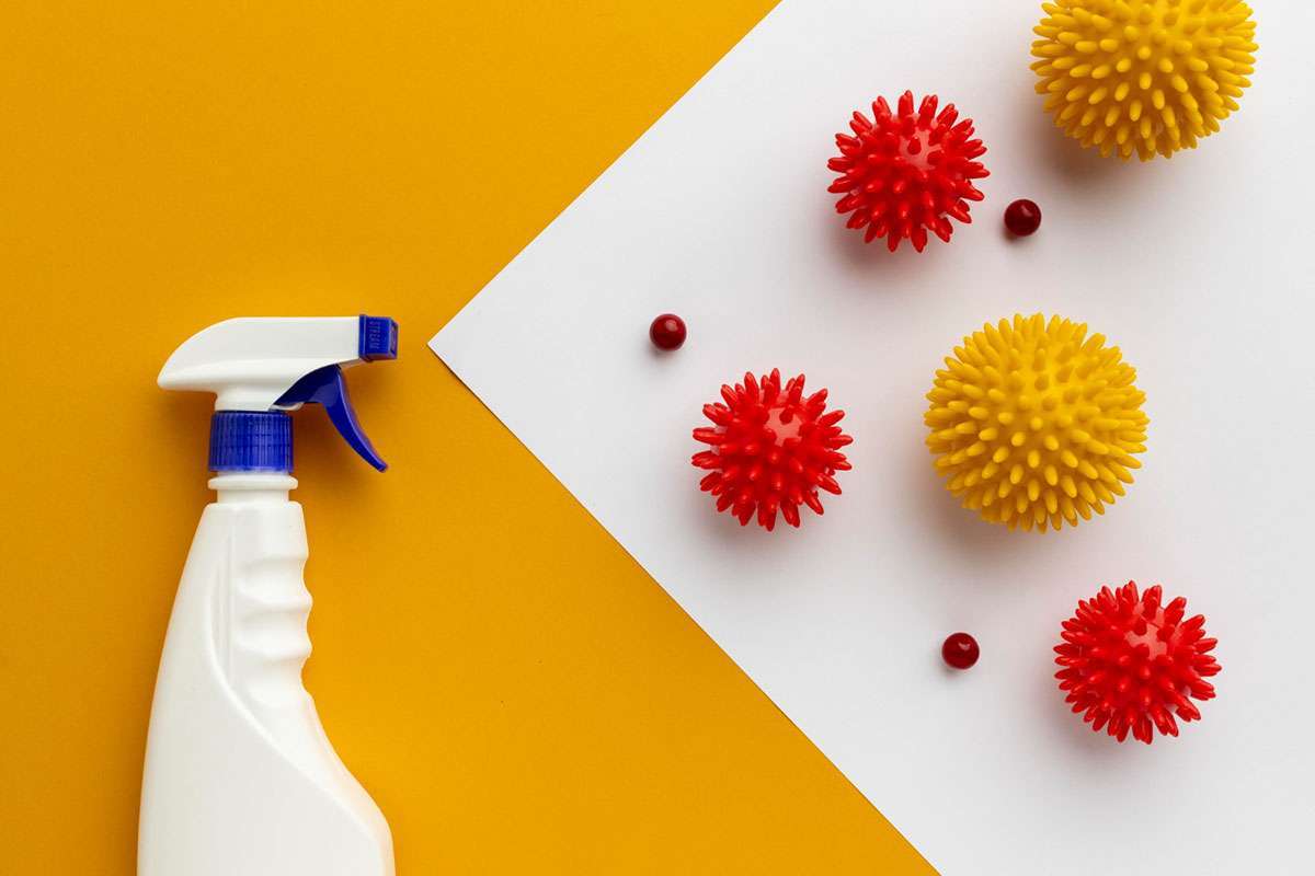 botella blanca tipo spray sobre fondo amarillo con efecto de pulverización en fondo blanco con unas pelotas amarillas y rojas con puas simbolizando virus