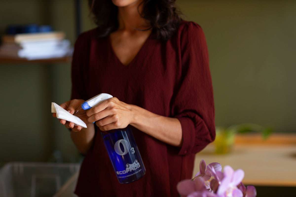 Plano medio mujer con spray ECOFROG pulverizando sobre una mopa.